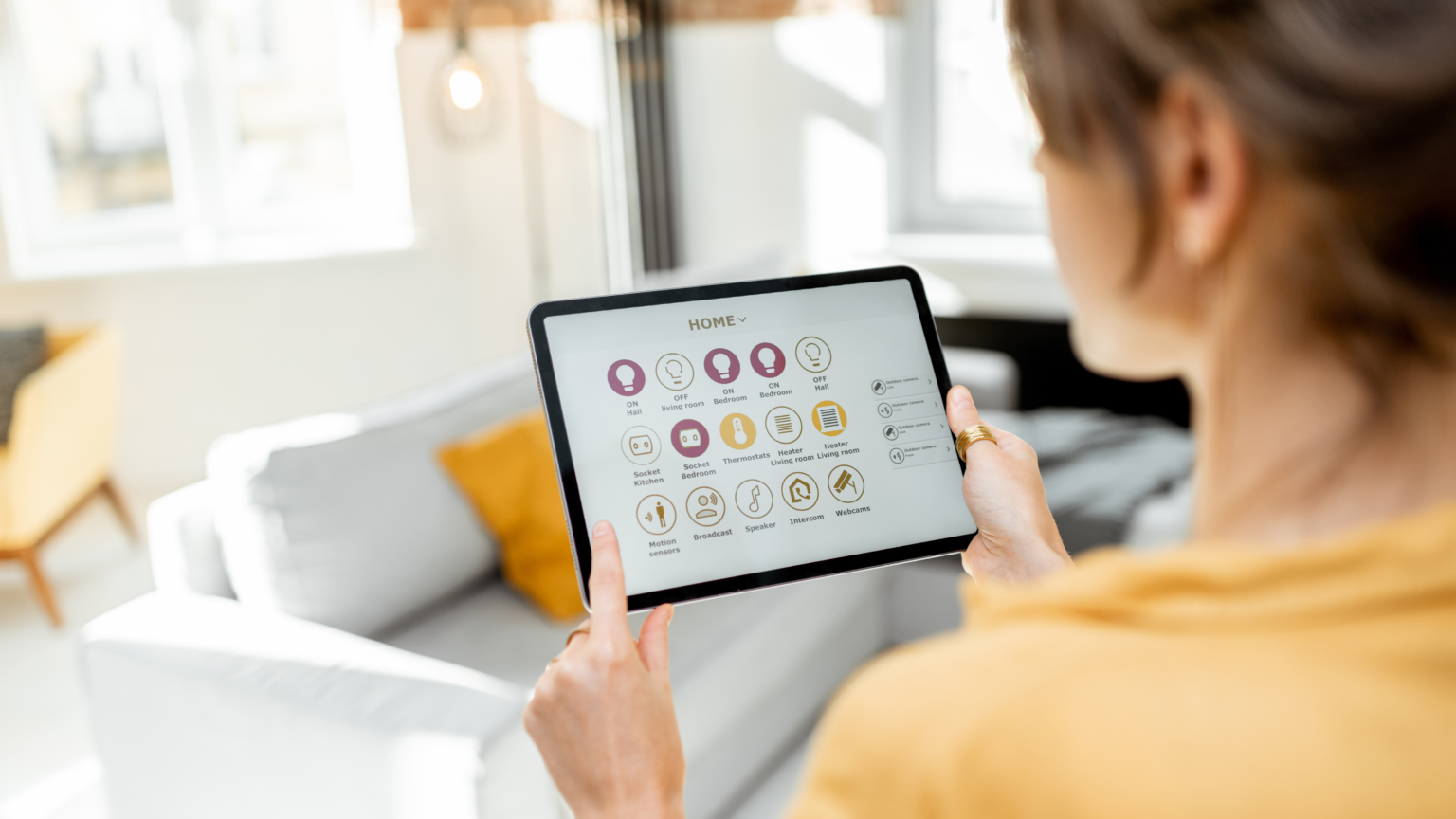 Foto de uma mulher segurando um tablet, manuseando sua casa inteligente, através da automação residencial.